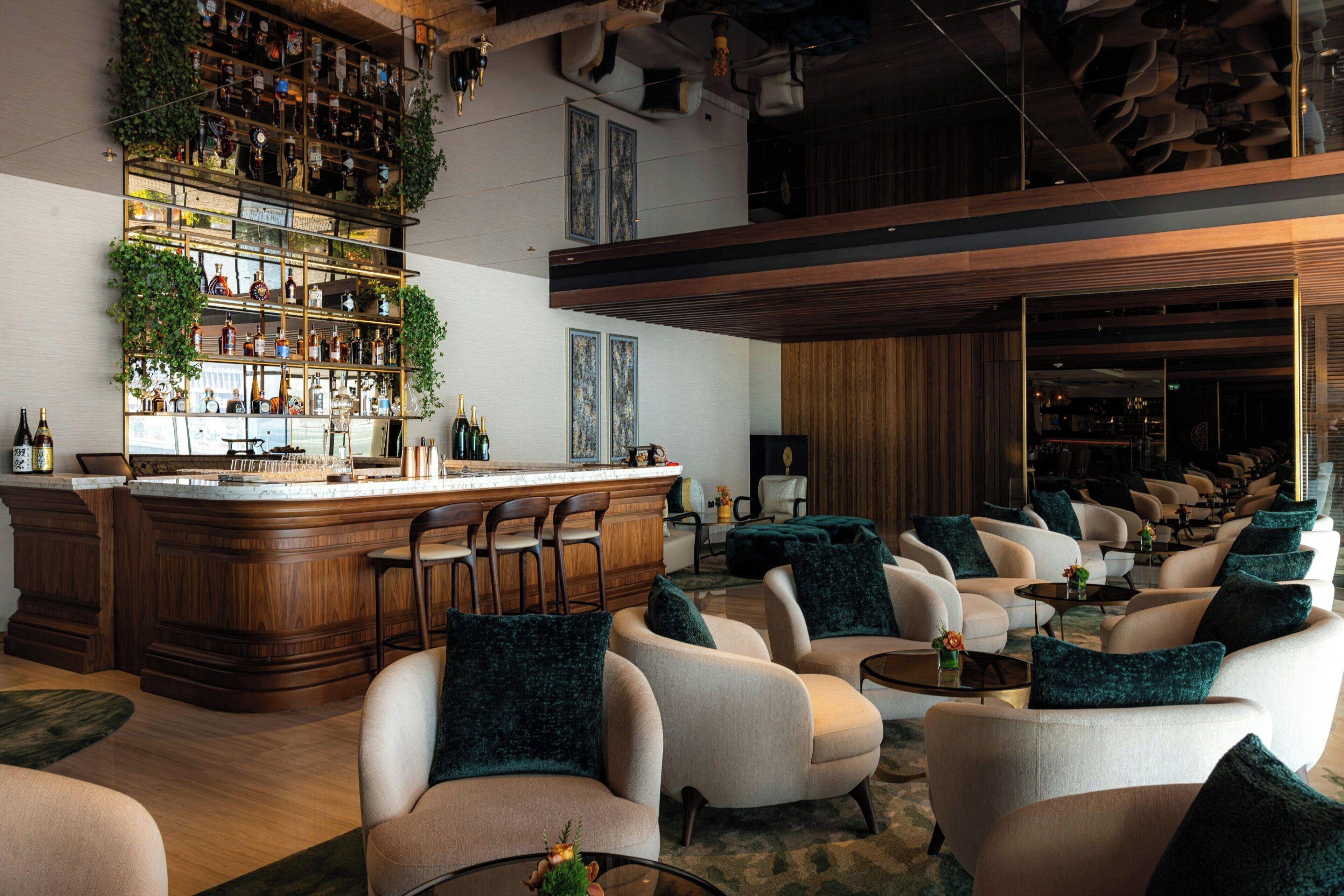 Zona de bar con mostrador de madera y diversas opciones de asiento, incluyendo sofás y sillas.