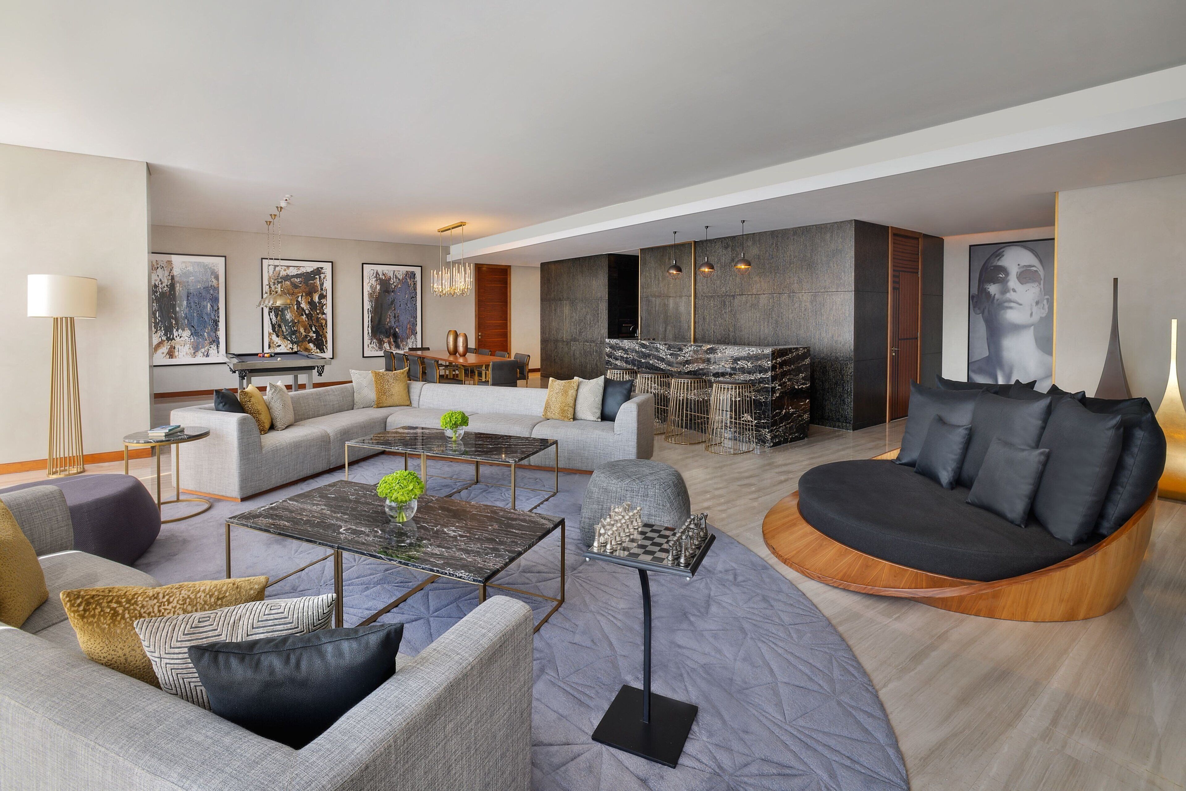 A modern living room with a sectional sofa, a round black sofa, and a coffee table with chess pieces.