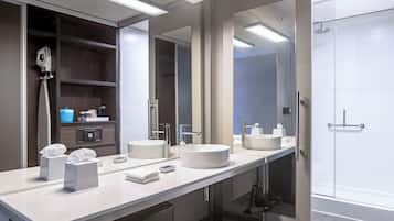A modern bathroom with two sinks, a large mirror, and a shower area.