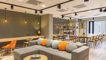 A modern office space with a sectional sofa, round tables, and a long dining table.