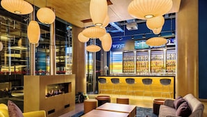 A modern bar area with a bar counter, seating, and a fireplace. - Aloft by Marriott Montevideo (Montevideo)