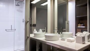 A modern bathroom with a glass-enclosed shower, two round sinks, and a large mirror.