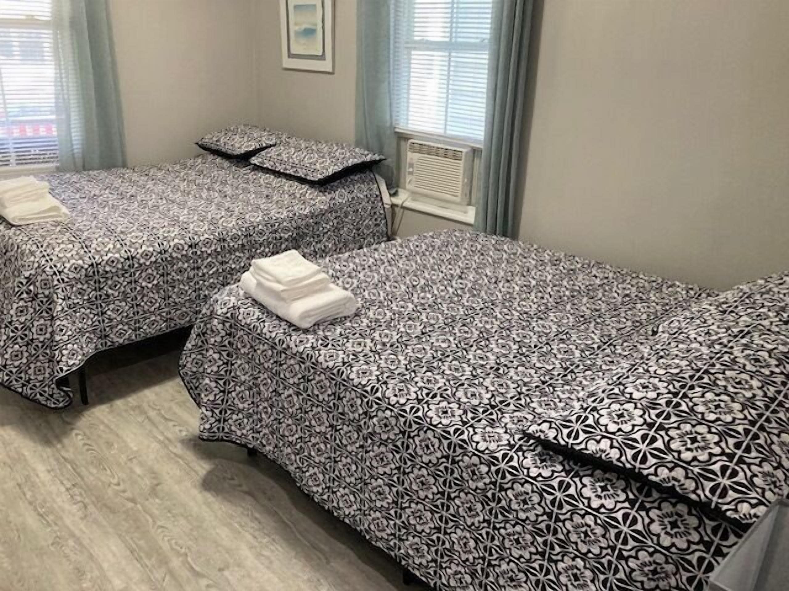 Dos camas individuales con ropa de cama estampada, un radiador y un cuadro enmarcado en la pared.