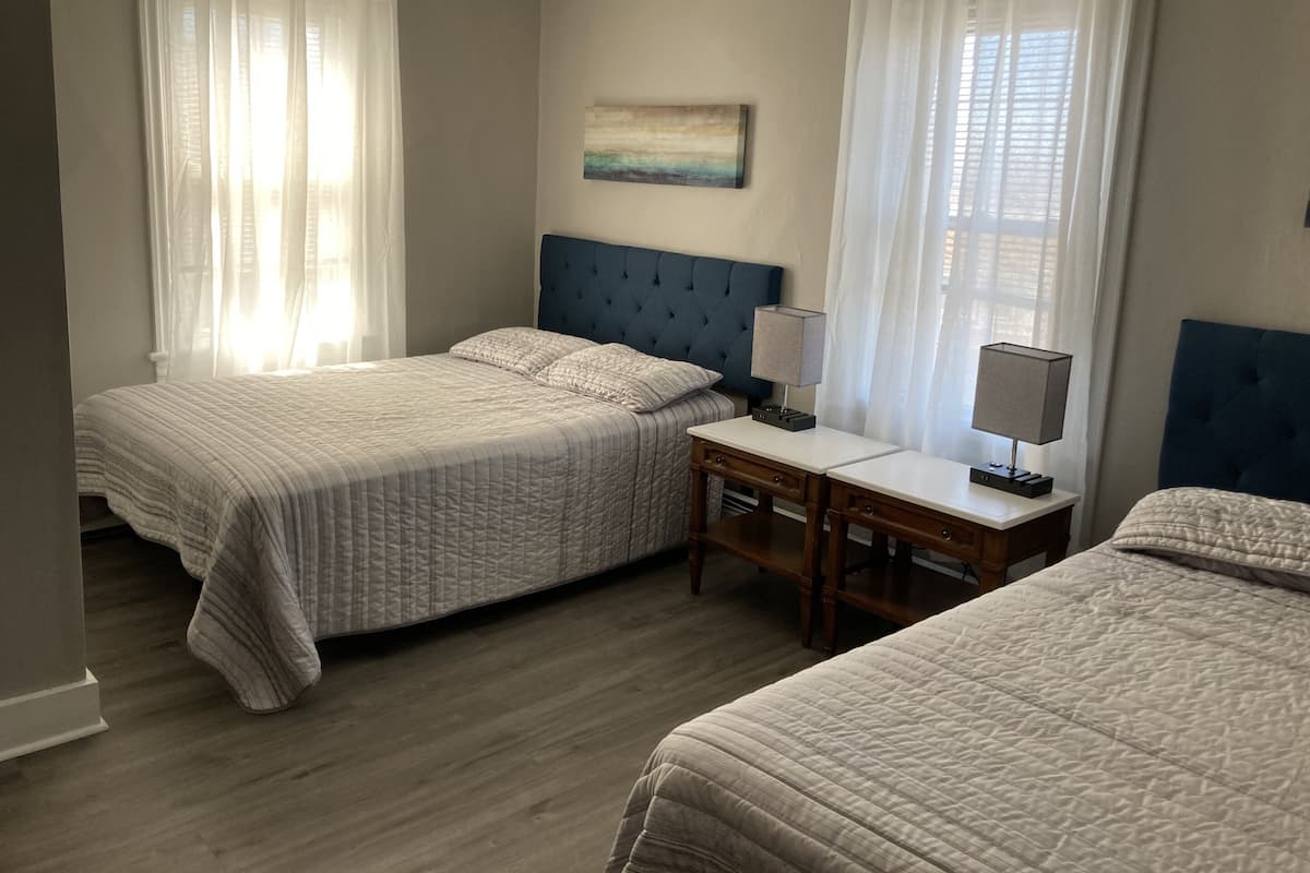 A bedroom with two beds, a nightstand with a lamp, and a painting on the wall.