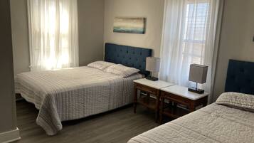 A bedroom with two beds, a nightstand with a lamp, and a painting on the wall.