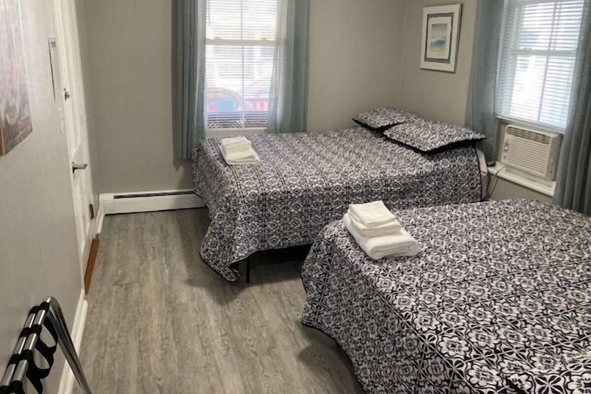 A room with two beds, a radiator, and a window with blinds.