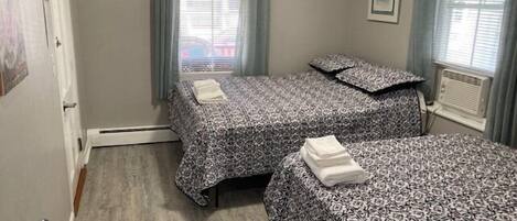 Quarto com duas camas, um radiador e uma janela com persianas.