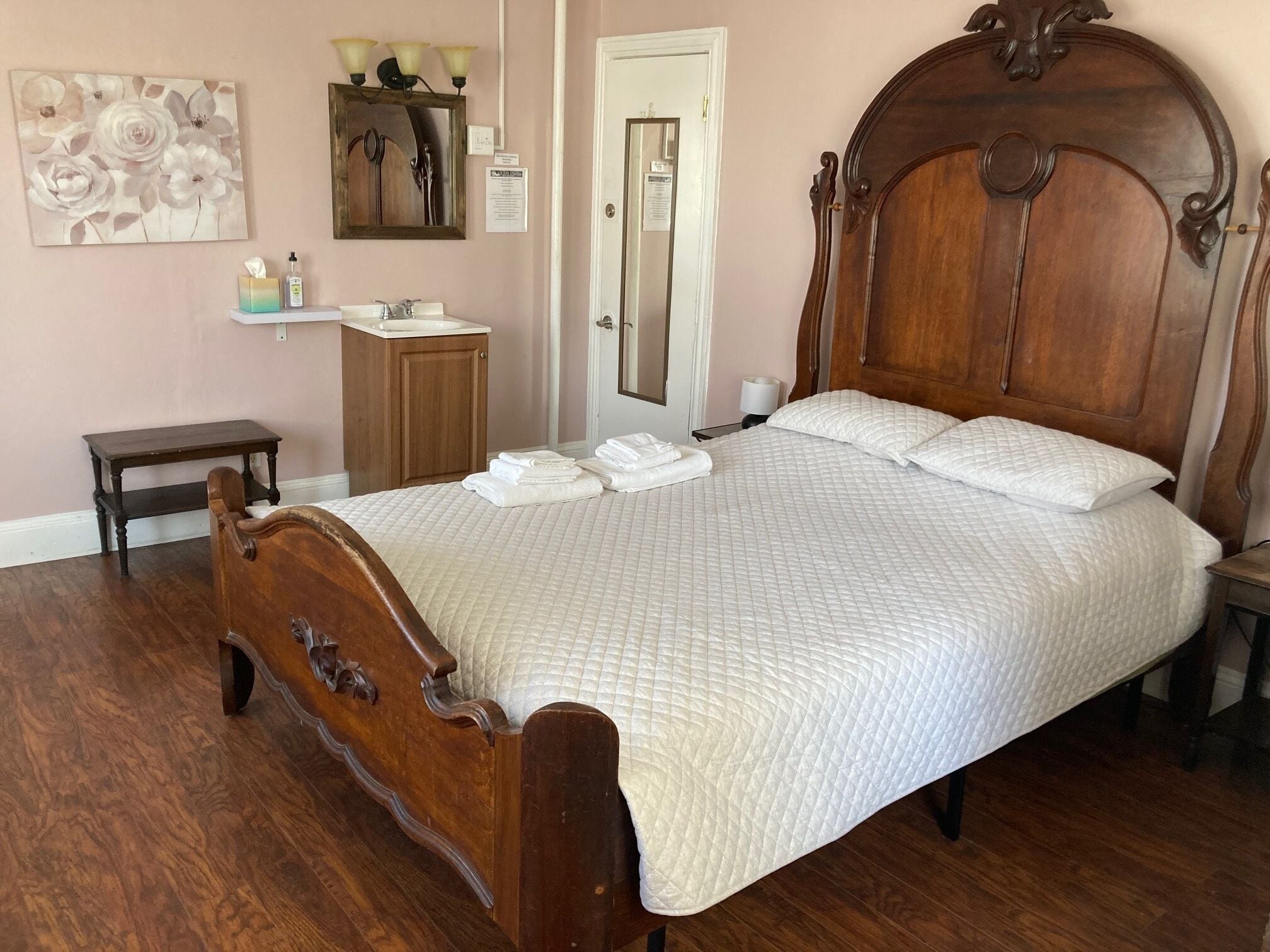 Ein Schlafzimmer mit einem hölzernen Bett, einem Nachttisch, einem kleinen Schrank und einer Wandleuchte.