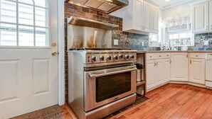 A kitchen with a stainless steel range, double oven, and a tiled backsplash. - Ocean Park Inn (Ocean Grove)