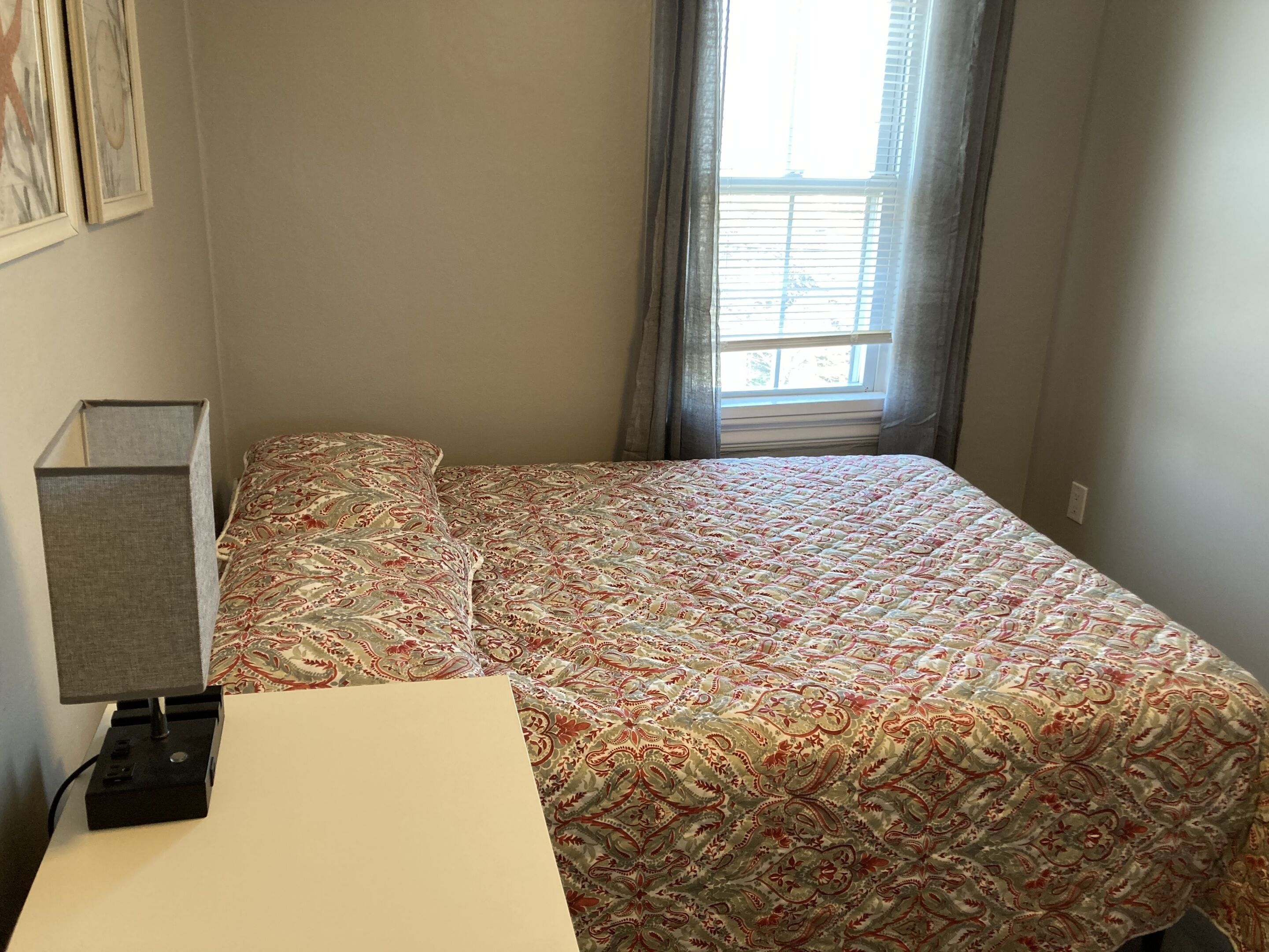 Un dormitorio con cama, escritorio y lámpara.