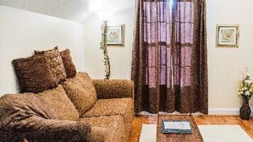 A living room with a sofa, a coffee table, and a curtain.