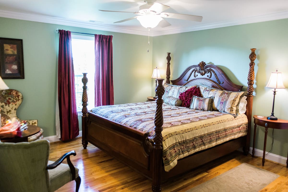 A four-poster bed with a wooden frame, two bedside lamps, and a floral-patterned bedspread.