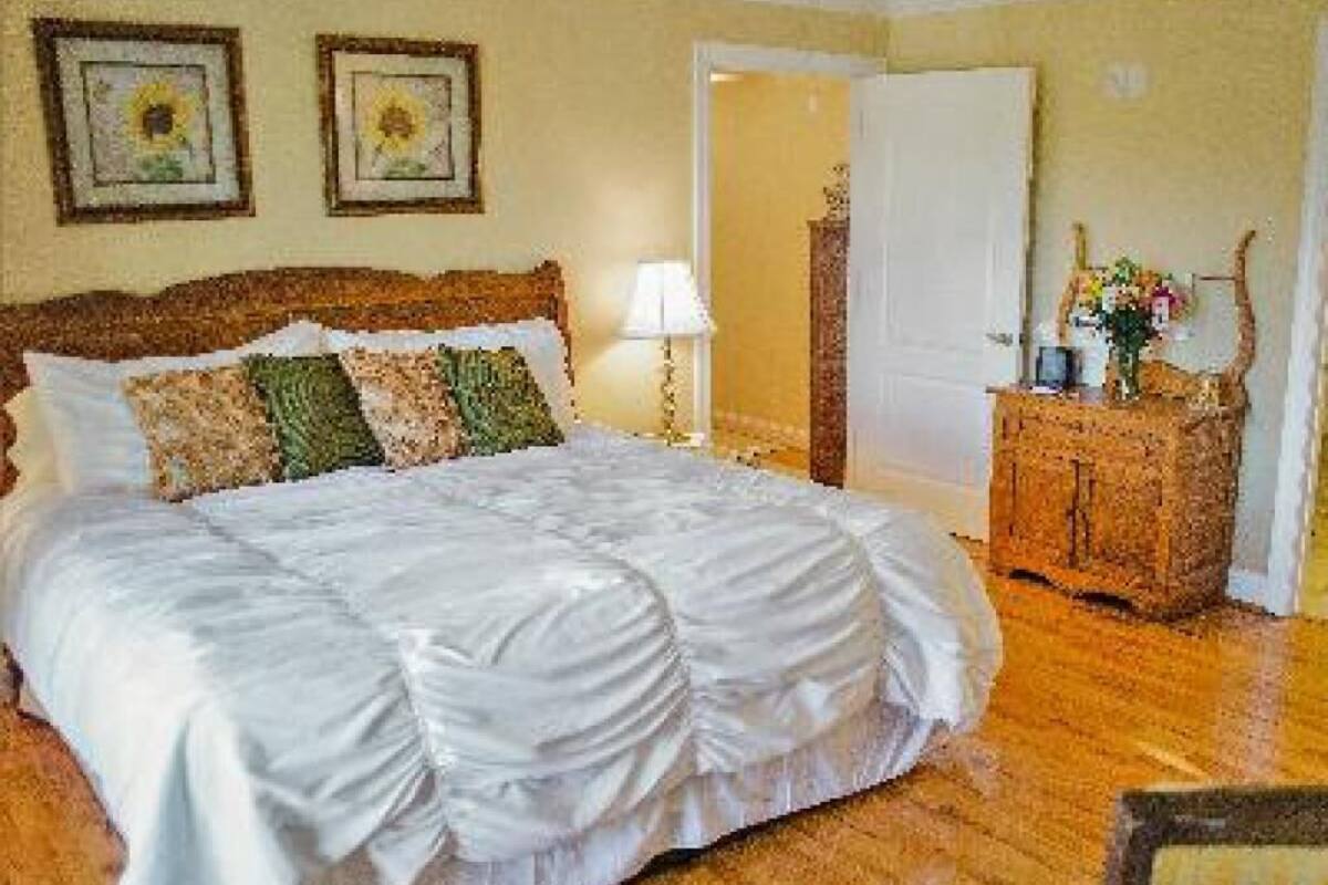 A neatly made bed with a wooden headboard, a bedside table with a lamp, and a dresser with a mirror.