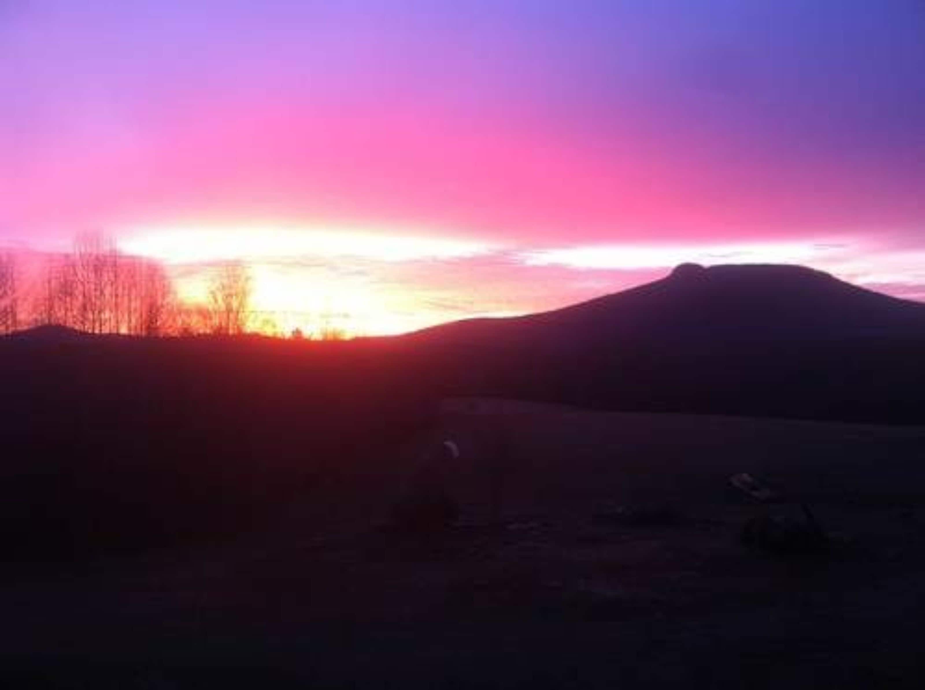 Eine Bergsilhouette vor einem Sonnenuntergangshimmel.