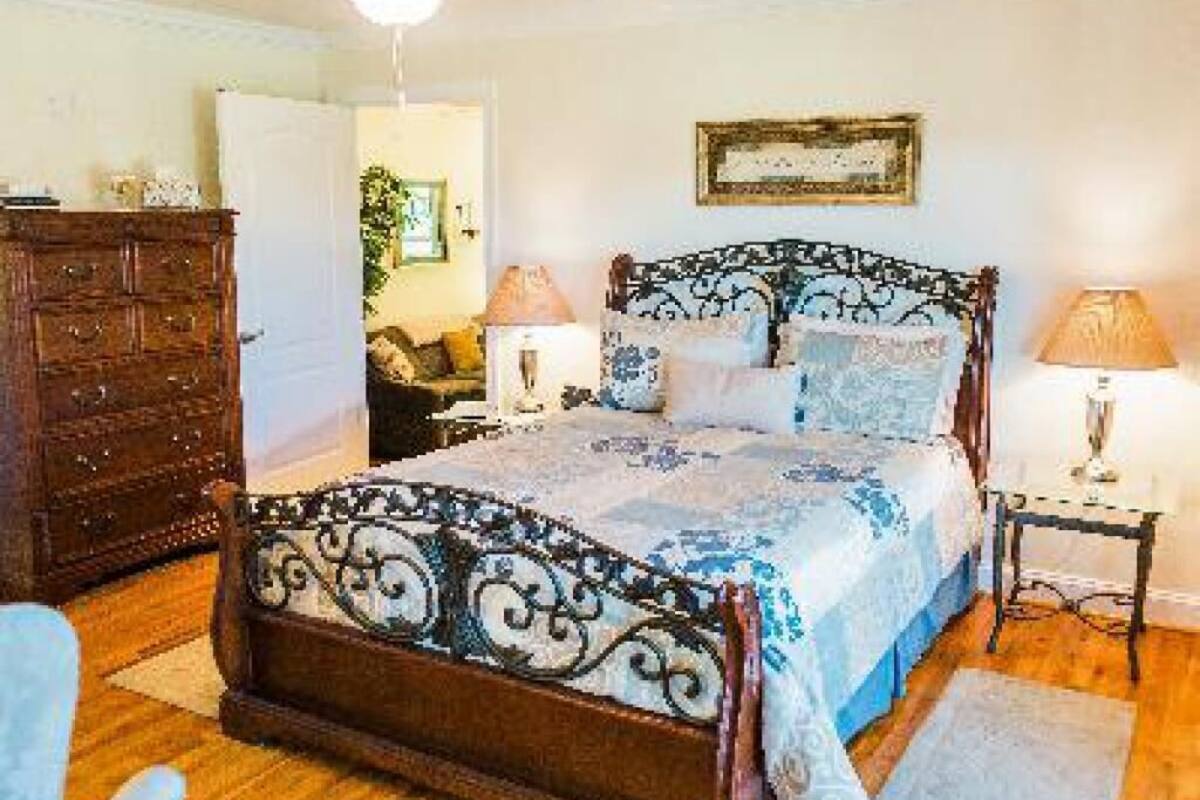 A bedroom with a wooden bed, a dresser, a nightstand, and a ceiling fan.
