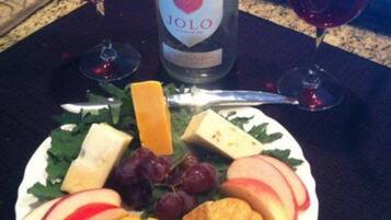 Un plato con queso, uvas, manzanas, galletas y una botella de vino Jolo.