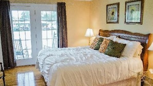 A bedroom with a large bed, a nightstand, a lamp, and a view of the outdoors through a sliding door. - A Mighty Oak B&B (Pinnacle)