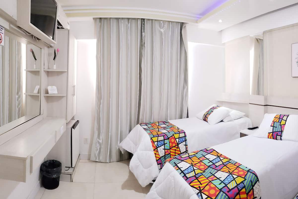 Ein Hotelzimmer mit zwei Betten, einem großen Spiegel, einem Kleiderschrank und einem Vorhang.