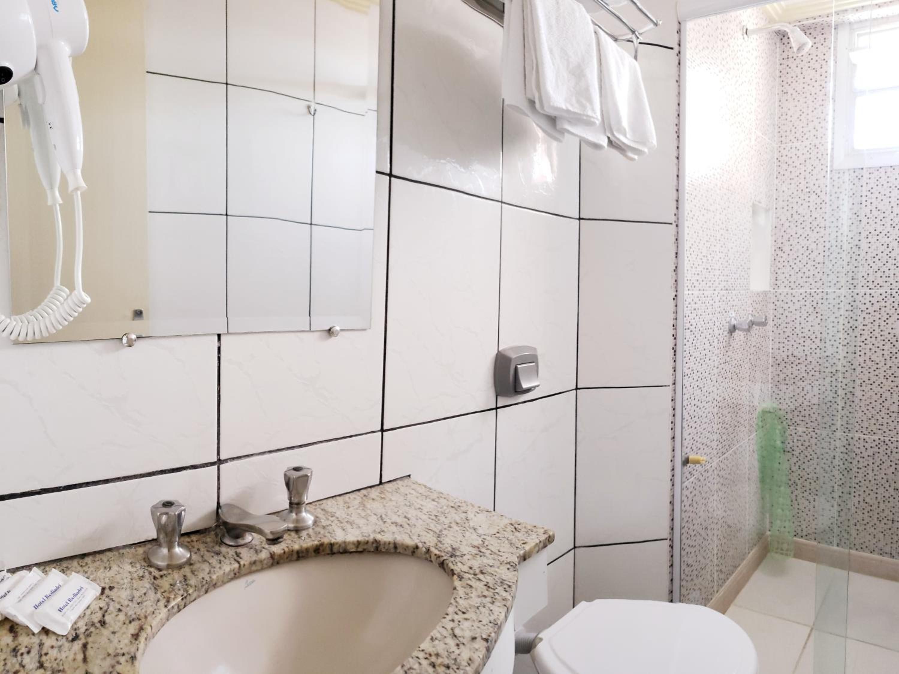 Un baño con lavamanos, espejo y ducha.