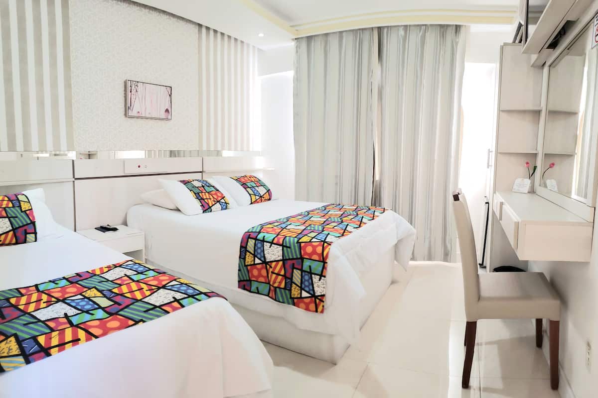 Ein Hotelzimmer mit zwei Betten, einem Schreibtisch und einem Spiegel.