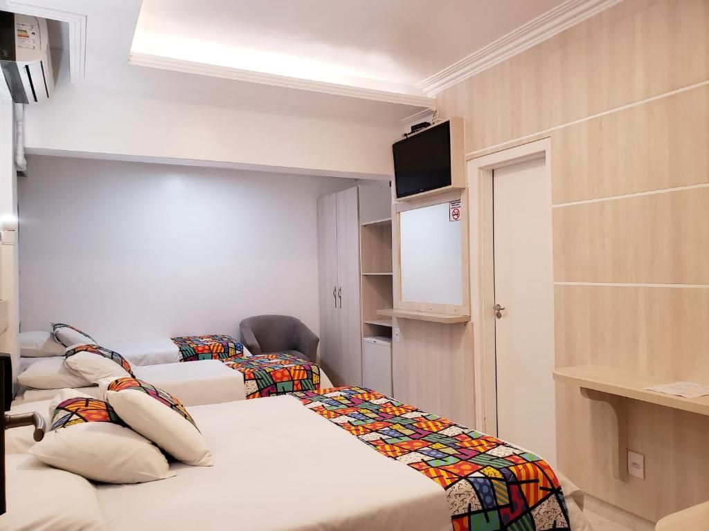 Habitación de hotel con dos camas, televisión, escritorio y armario.