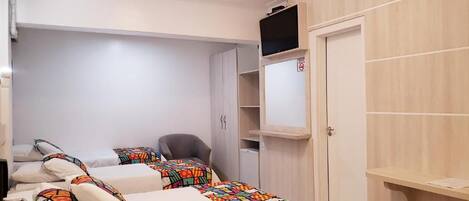 Habitación de hotel con dos camas, televisión, escritorio y armario.
