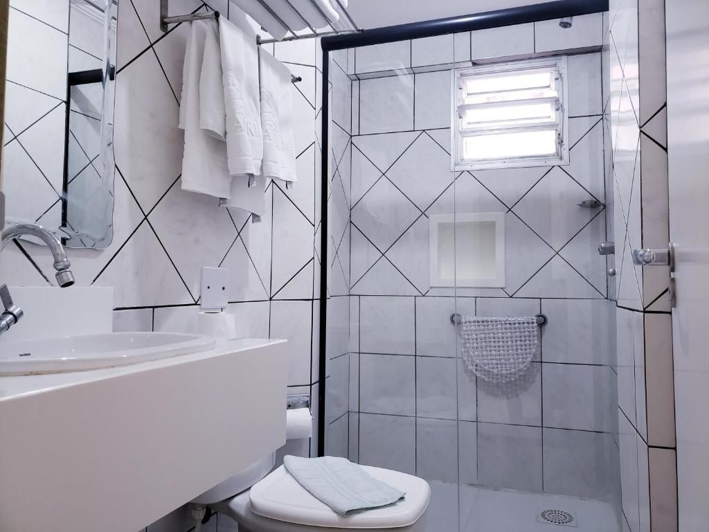 Un baño con lavamanos blanco, espejo y retrete.