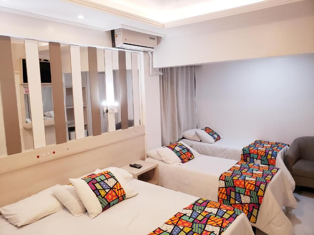 Une chambre d’hôtel avec deux lits, une armoire, un climatiseur et un canapé.