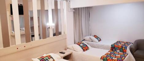 Habitación de hotel con dos camas, un armario, aire acondicionado y un sofá.