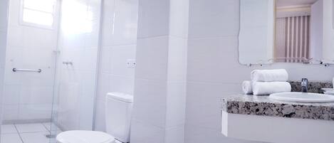 Un baño moderno con cabina de ducha de vidrio, inodoro blanco y encimera de mármol con lavabo y toallero.