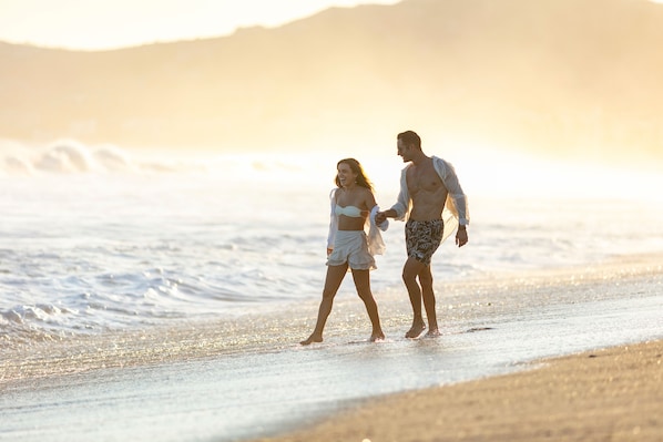 A couple walking on a beach with waves in the background. - Drift San Jose del Cabo, a Member of Design Hotels (San José del Cabo)