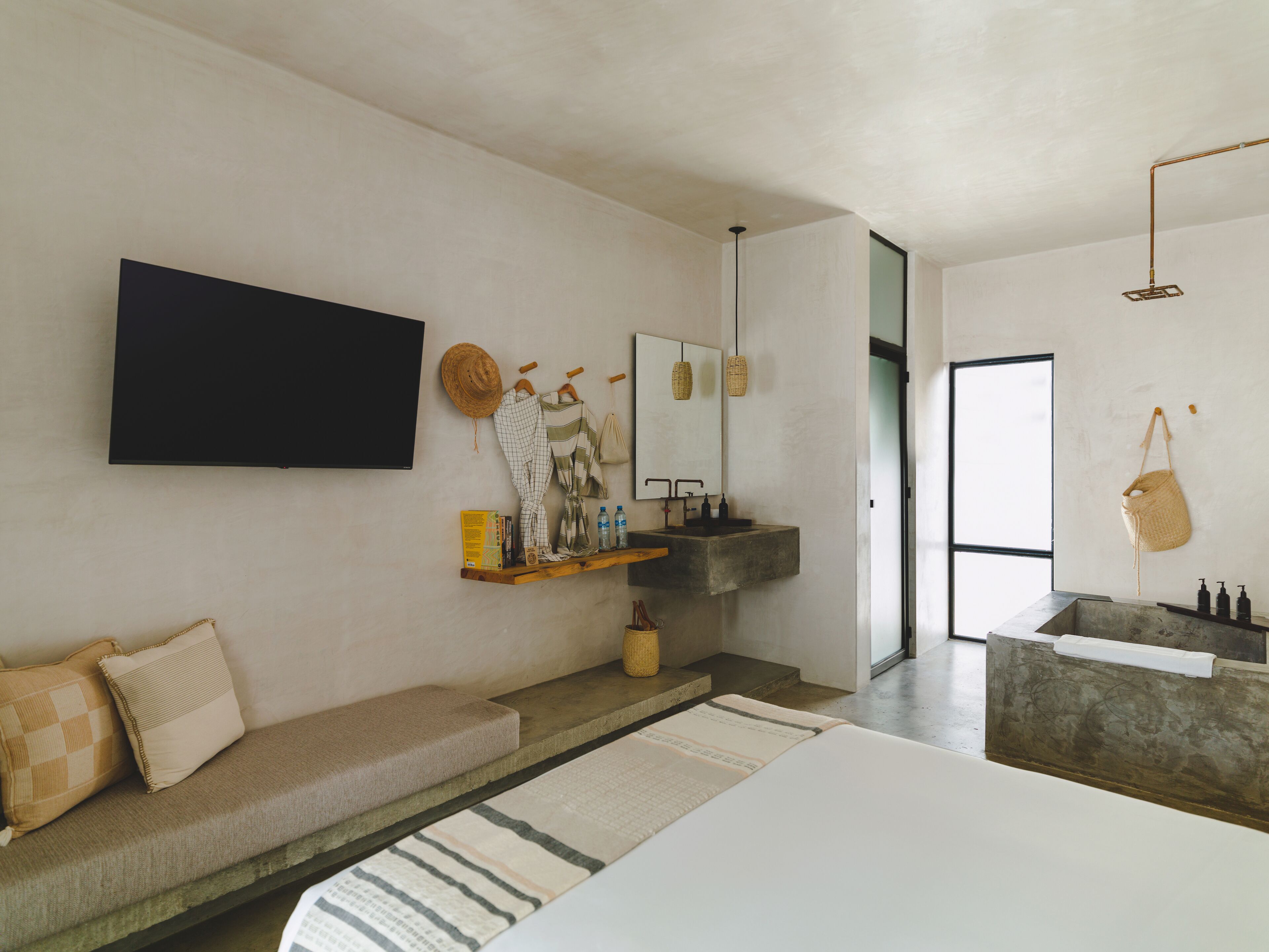 A modern bathroom with a large mirror, a built-in sink, and a flat-screen TV mounted on the wall.
