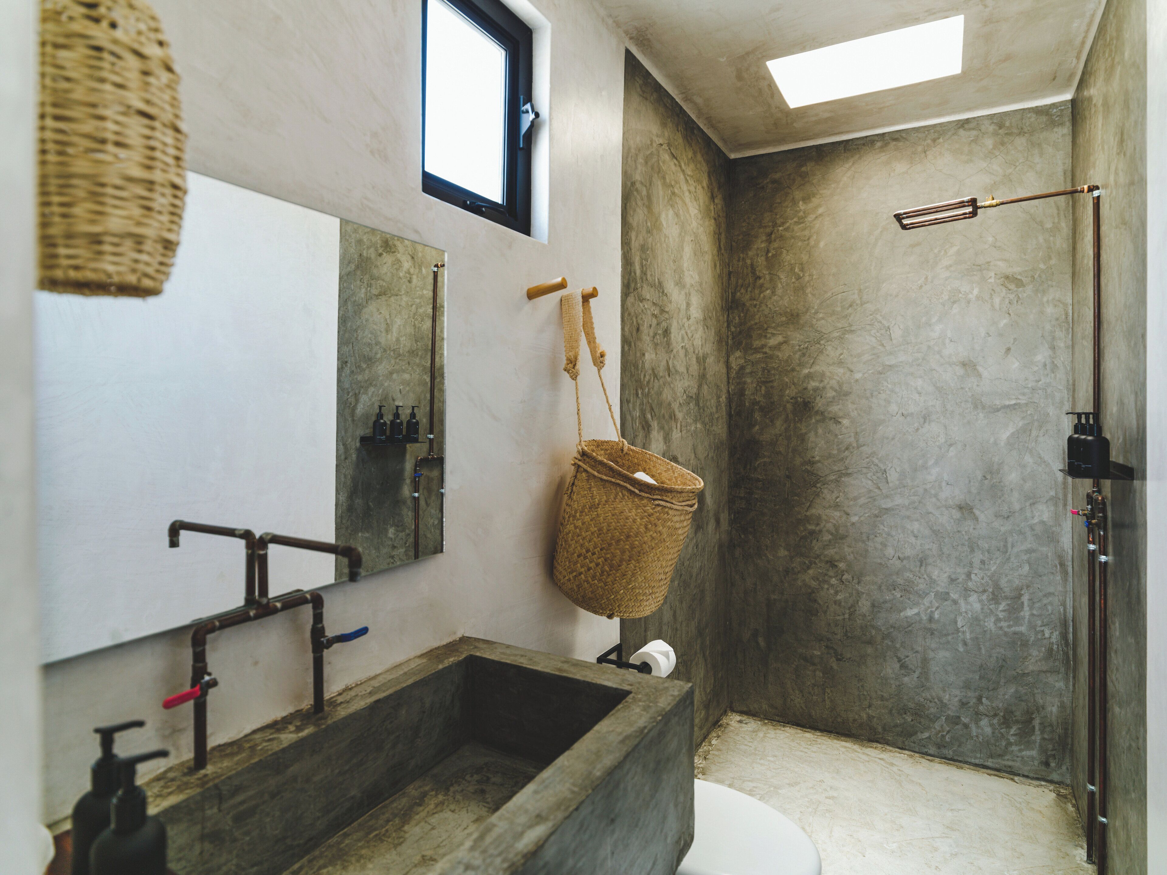 A bathroom with a large wooden sink, a mirror, a hanging basket, and a shower area.