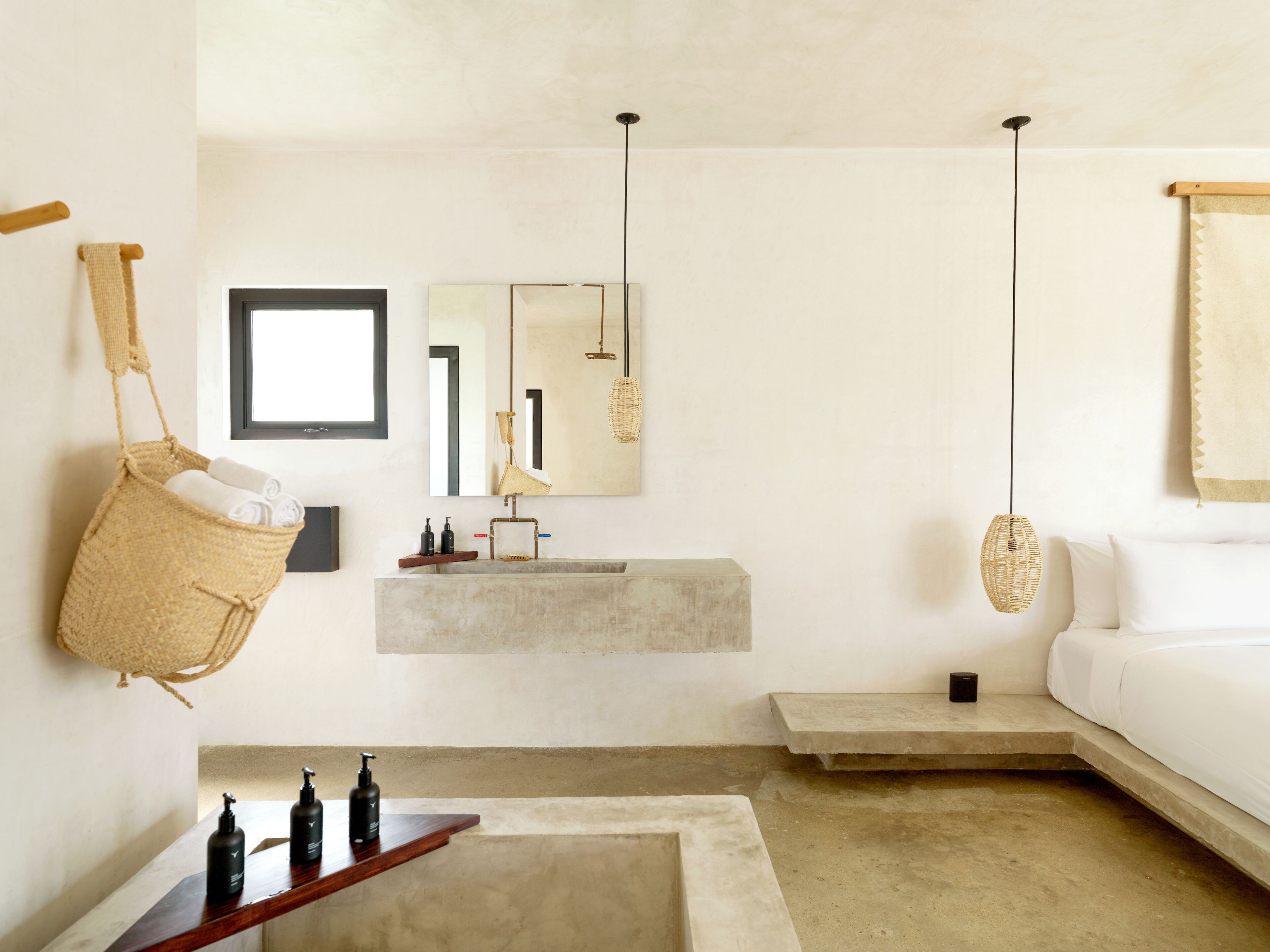 A minimalist bathroom with a concrete sink, hanging bathrobe, and a large mirror.