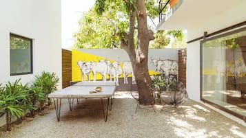 Un patio con una mesa y sillas, un árbol y un mural de toros en la pared.