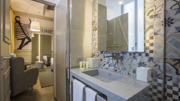 A modern bathroom with a large mirror, a sink, and a shower area.