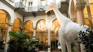 A large indoor giraffe statue in a hotel lobby with arched ceilings, chandeliers, and potted plants. - Hotel Indigo Milan - Corso Monforte by IHG (Milan)