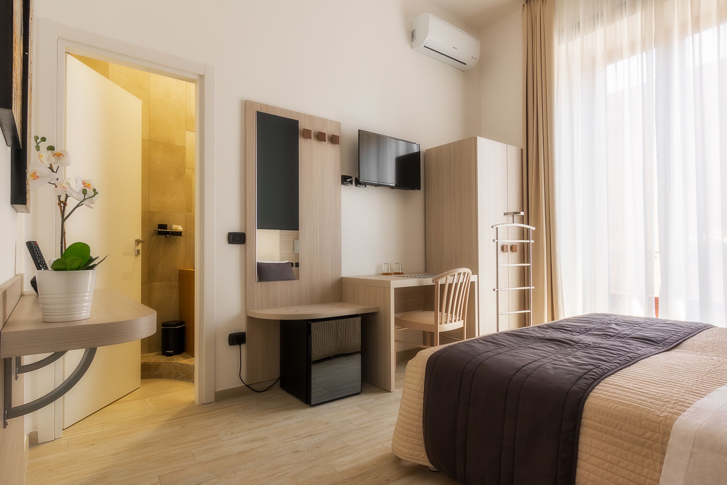 Una habitación de hotel moderna con cama, escritorio y televisor.