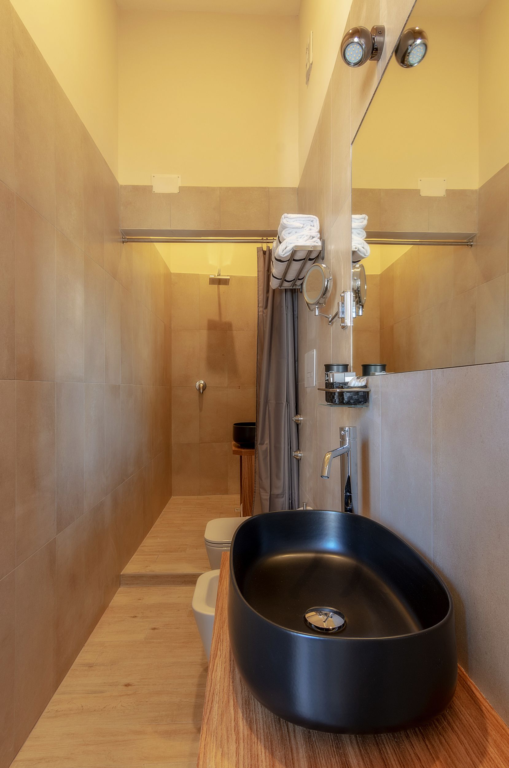 Un bany modern amb un lavabo negre, una dutxa i un vàter.