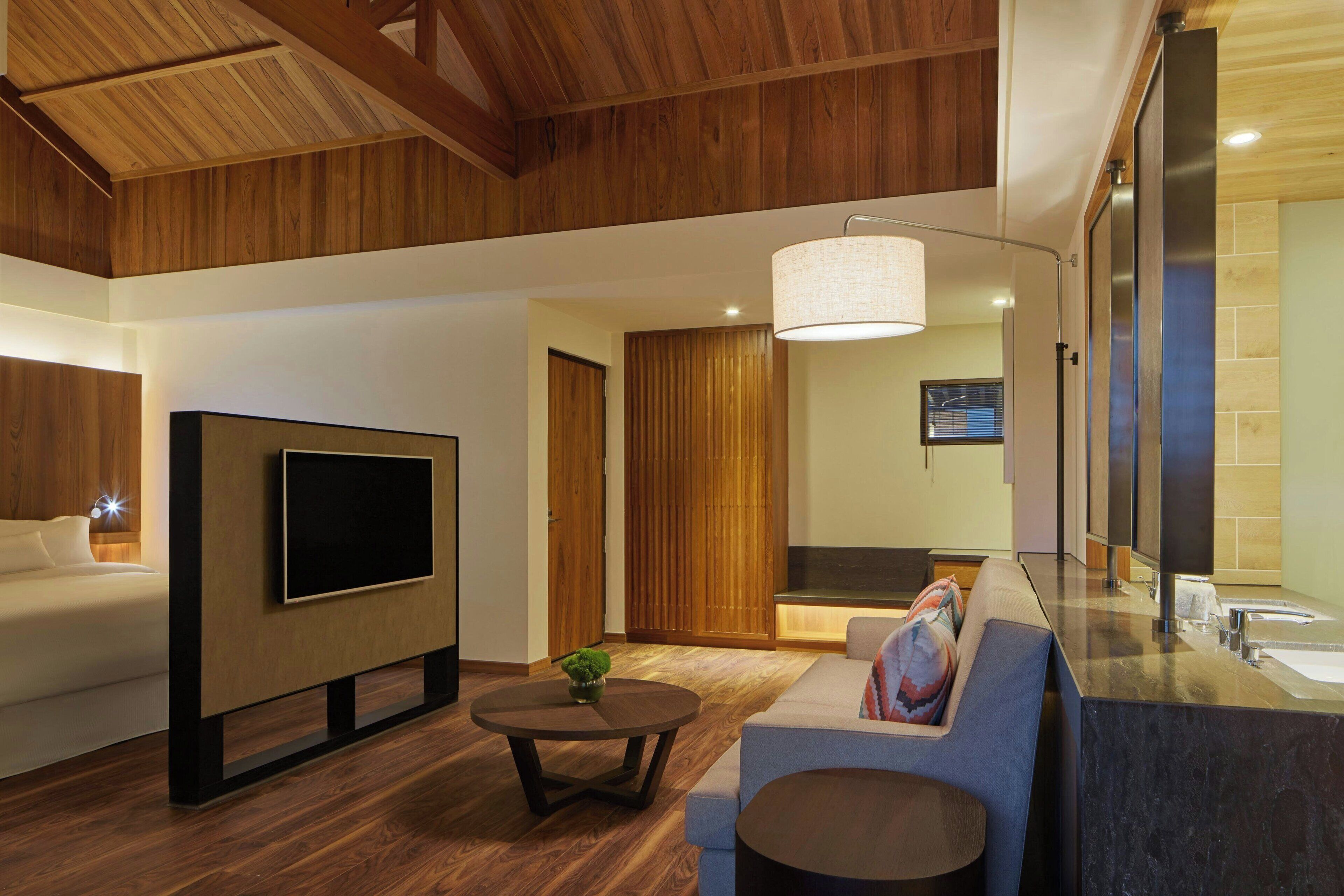 Una sala de estar moderna con un televisor de pantalla plana, un sofá, una mesa de centro y techo de madera.