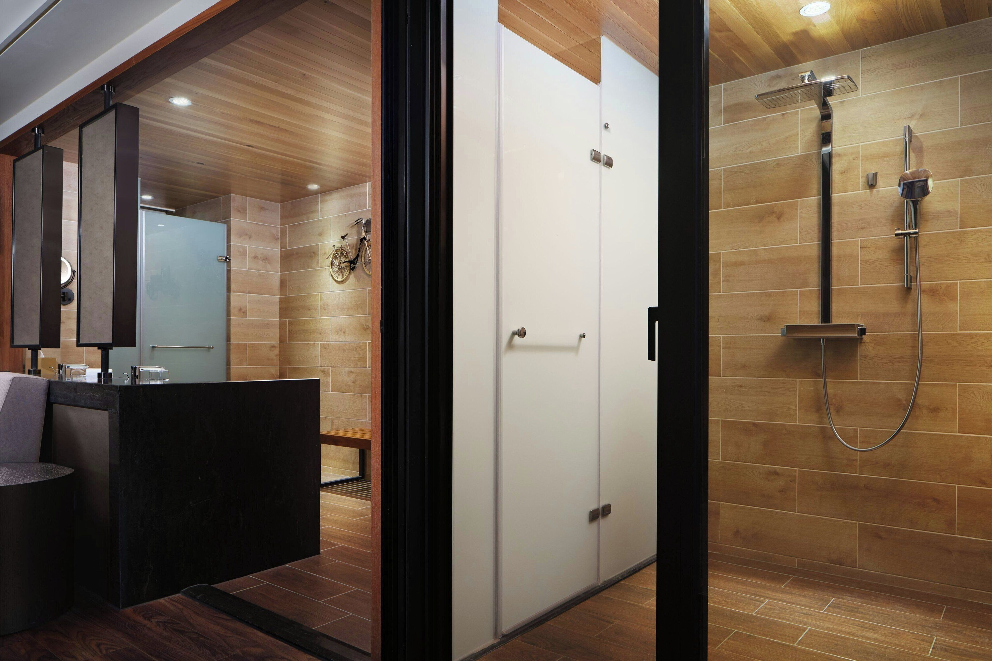 A modern bathroom with wooden walls, a shower area, and a vanity with a mirror.