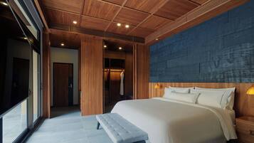 A modern bedroom with a large bed, wooden ceiling, and a view through a glass door.