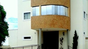 Un immeuble à plusieurs étages doté d’une façade incurvée, de grandes fenêtres et d’une entrée centrale avec des marches.