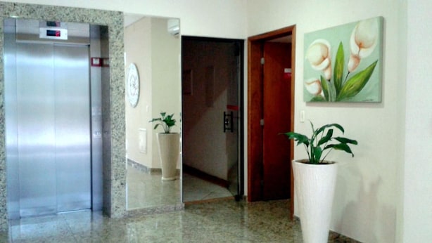 Un ascenseur, une plante en pot et une porte dans un couloir.
