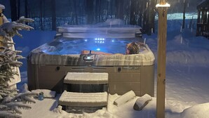 Un jacuzzi rodeado de nieve con un poste de madera al frente.