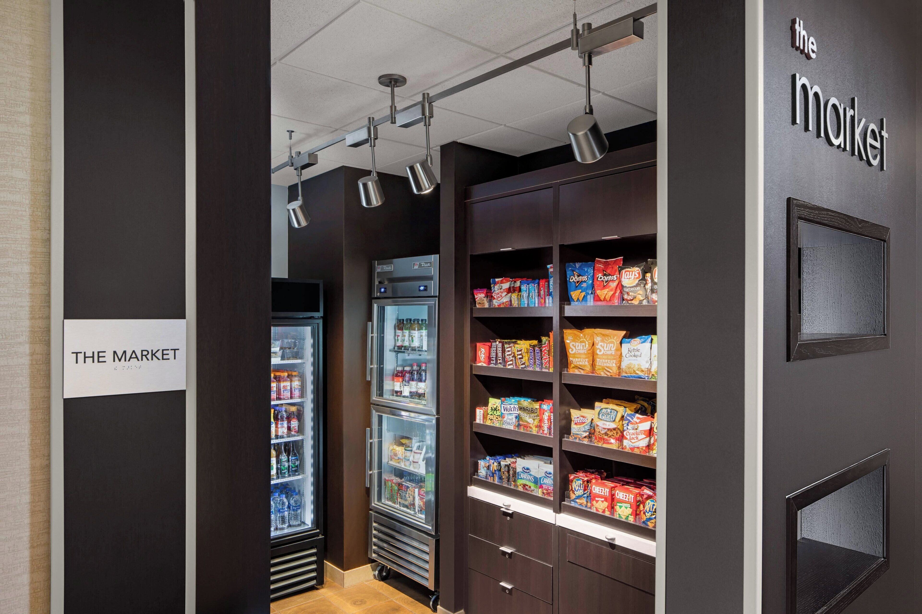 A section of a hotel with a refrigerated display case and shelves stocked with snacks.