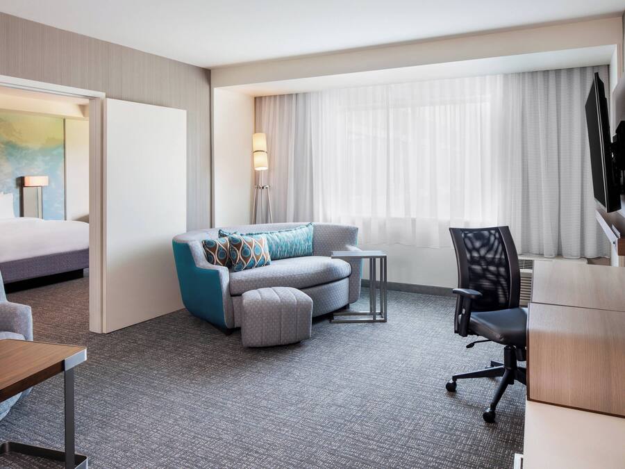 Una habitación de hotel con cama, sofá, escritorio, silla y lámpara.