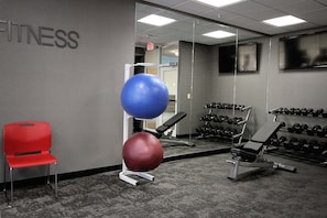 A gym with exercise equipment, a red chair, and a wall with the word "FITNESS". - Fairfield Inn & Suites by Marriott London (London)