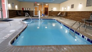 An indoor swimming pool with clear lane markings, a lifeguard chair, and a changing room entrance. - Fairfield Inn & Suites by Marriott London (London)