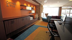 A modern conference room with a reception desk, a computer setup, and a seating area. - Fairfield Inn & Suites by Marriott London (London)